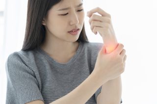 unhappy asian woman hand touch wrist with hand hurt from work or exercise white background